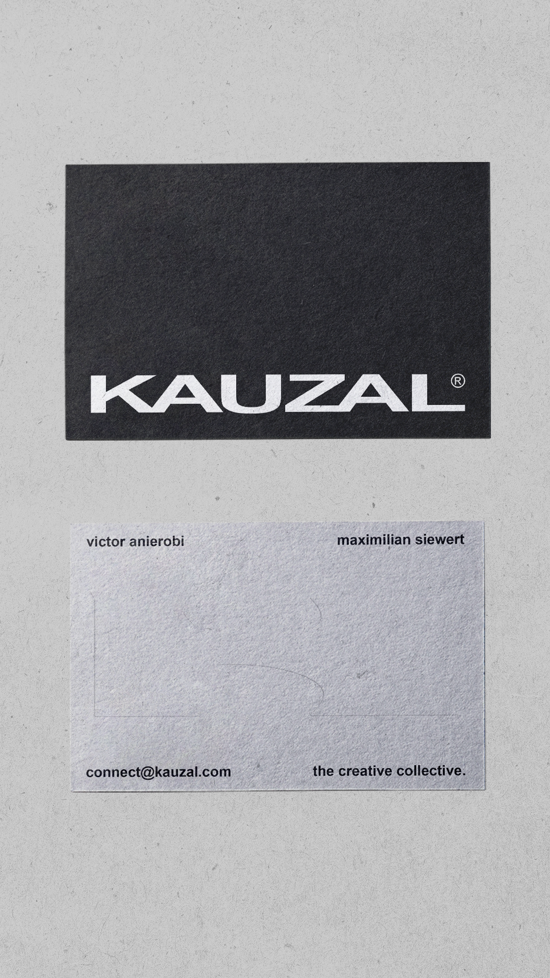 Front and back of the updated KAUZAL business cards on a textured grey surface.